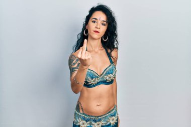 Young woman wearing bindi and traditional belly dance clothes showing middle finger, impolite and rude fuck off expression 