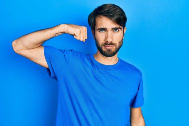 Gündelik kıyafetler giyen genç İspanyol adam güçlü kol kası gösteren, kendinden emin ve gururlu biri. 