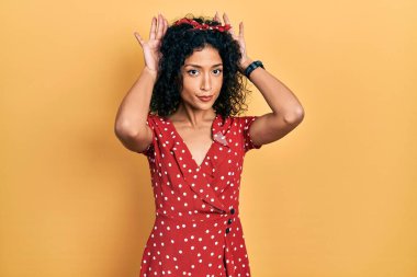 Yazlık elbise giyen genç Latin kız tavşan kulağı hareketi yapıyor. Avuçlarıyla alaycı ve şüpheci görünüyor. Paskalya tavşanı konsepti. 