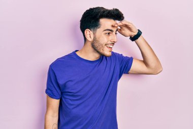 Gündelik tişört giyen genç İspanyol adam çok mutlu ve gülümseyerek başını kaldırmış uzaklara bakıyor. arama kavramı. 