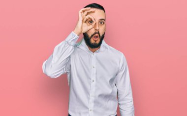 Sakallı, iş gömleği giyen, şaşırmış yüz ifadesiyle şok olmuş, parmaklarından bakan genç bir adam. İnançsız ifade. 