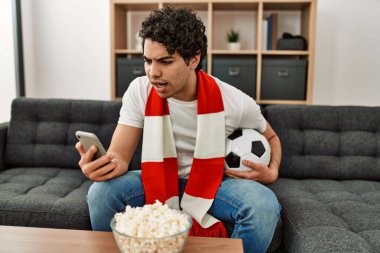 Genç İspanyol adam futbol maçı izliyor ve takımını evde destekliyor..