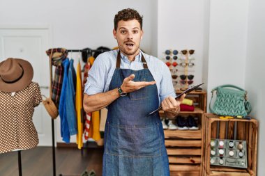 Perakende mağazasında yönetici olarak çalışan yakışıklı genç adam avuç içi açık bir şekilde fotokopi alanını gösteriyor, gülümseyerek mutlu bir şekilde gülümsüyor. 