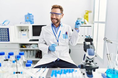 Bilim adamının laboratuvarında çalışan orta yaşlı bir adam gülümsüyor. 