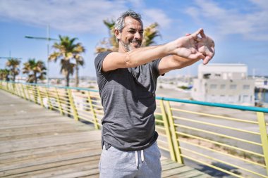 Orta yaşlı İspanyol adam spor giyer, sokakta esniyor.