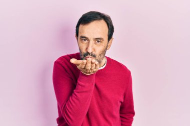 Orta yaşlı İspanyol bir adam, gündelik kıyafetler giyip kameraya bakıyor ve havada el sallayarak öpüşüyor. Güzel ve seksi. aşk ifadesi. 