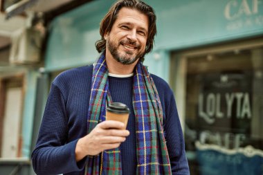 Orta yaşlı yakışıklı adam kasabada bir fincan kahve içiyor.