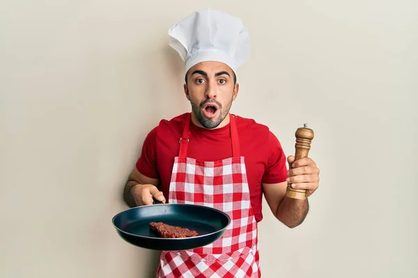 Mladý Hispánec Profesionální Kuchařské Uniformě Čepici Vaření Hovězí Strach Šokován — Stock fotografie
