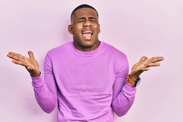 腕を上げて成功のために狂気と狂気を祝うカジュアルなピンクのセーターを着ている若い黒人男性は興奮叫んで目を閉じています 勝者のコンセプト — ストック写真