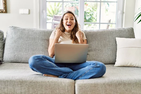 Linda Jovem Morena Sentada Sofá Usando Laptop Casa Celebrando Surpreso — Fotografia de Stock