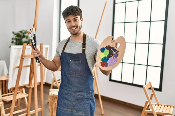 Joven Artista Hispano Sonriendo Feliz Sosteniendo Pinceles Paleta Estudio Arte — Foto de Stock