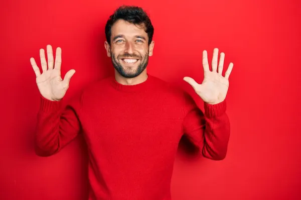 Przystojny Mężczyzna Brodą Czerwonym Swetrze Pokazuje Wskazuje Palcami Numer Dziesięć — Zdjęcie stockowe