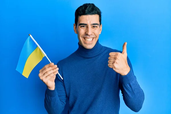 Snygg Hispanic Man Bär Ukrainska Flaggan Ler Glad Och Positiv — Stockfoto