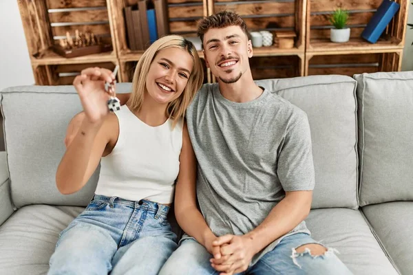 Genç Beyaz Bir Çift Gülümsüyor Kanepede Yeni Evlerinin Anahtarını Tutuyorlar — Stok fotoğraf