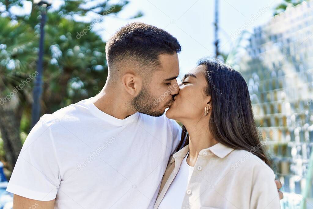 Young latin couple kissing and hugging standing at the city.