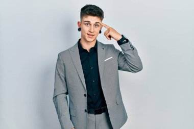 Kulakları genişlemiş, iş ceketi giymiş, gülümseyen, tek parmakla işaret eden beyaz çocuk, harika bir fikir ya da düşünce, iyi bir hafıza. 