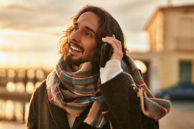 Genç İspanyol adam gülümsüyor. Şehirdeki akıllı telefondan konuşuyor..