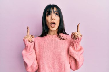 Kakülleri olan genç esmer kadın şaşkın şaşkın yukarı bakıyor ve parmaklarını gösterip kollarını kaldırıyordu.. 