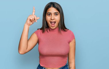Gündelik tişört giyen genç İspanyol kız başarılı bir fikri işaret ediyor. Heyecanlı ve mutlu. Bir numara.. 