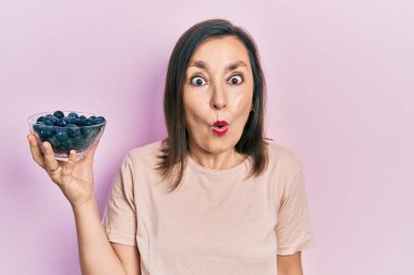 Orta yaşlı İspanyol kadın elinde yaban mersini tutarken ağzı açık kalmış, korkmuş ve hayrete düşmüştü. 