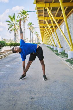 Young hispanic man stretching body muscles outdoors