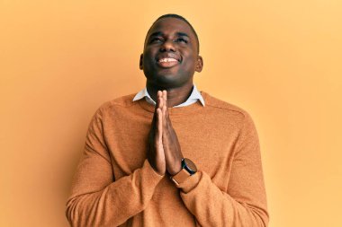 Genç Afro-Amerikalı bir adam günlük giysiler giyip elleri bağlı yalvarıyor ve dua ediyor. Yüzünde umut ifadesi var. Çok duygusal ve endişeli. Yalvarıyor. 