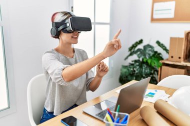 Ofiste sanal gerçeklik gözlüğü kullanan genç beyaz bir mimar kadın..