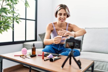 Makyaj hocası olan beyaz bir kız evdeki kanepede oturuyor..