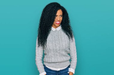 Orta yaşlı Afro-Amerikalı kadın günlük kıyafetler giyiyor gülümsüyor ve yan tarafa bakıyor ve düşünüyor.. 