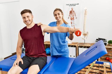 Genç İspanyol fizyoterapist kadın klinikteki adama kol rehabilitasyonu uyguluyor..