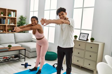 Genç Latin sporcu çift gülümseyerek evde mutlu bir antrenman yapıyor..