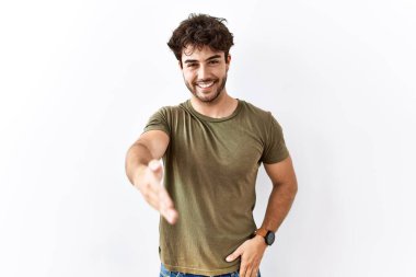 İzole edilmiş beyaz arka planda duran İspanyol bir adam dostça bir selamlama ve hoş geldin hediyesi olarak el sıkışmayı sunuyor. başarılı iş. 
