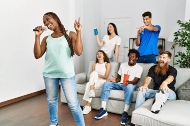 Bir grup genç arkadaş evde mikrofon kullanarak şarkı söylüyor..