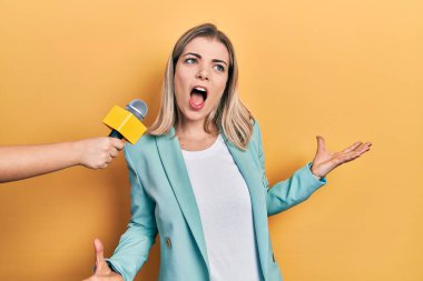 Güzel beyaz kadın mikrofon tutan bir muhabir tarafından sorgulanıyor. Deli gibi bağırıyor ve bağırıyor. Saldırgan bir ifade ve kollar havada. hüsran kavramı. 