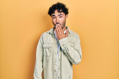 Gündelik kıyafetler giyen genç İspanyol adam ağzıyla ağzını kapatmaktan sıkılmış. Huzursuz ve uykulu.. 