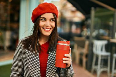 Genç İspanyol kadın gülümsüyor. Mutlu bir şekilde içiyor. Şehirde kahve içiyor..