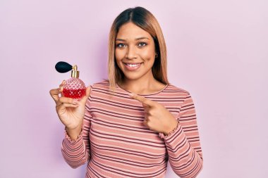 Güzel İspanyol kadın, elinde parfüm tutarken gülümsüyor. 