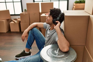 Genç İspanyol adam yeni evinde yerde oturmuş müzik dinliyor..