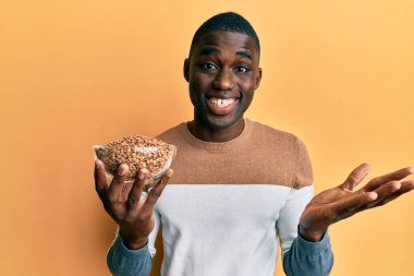 Genç Afrikalı Amerikalı adam mercimeği fırına verip zaferi mutlu bir gülümsemeyle kutluyor ve kazanan el kaldırıyor. 