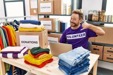 Orta yaşlı bir adam dizüstü bilgisayarla çalışıyor gülümsüyor telefonla el ve parmak hareketleri yapıyor telefonda konuşuyor gibi. iletişim kavramları. 