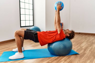 Genç İspanyol adam spor merkezinde formda top kullanıyor.