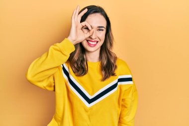 Gündelik kıyafetler giyen genç İspanyol kız el hareketleriyle gülümsüyor, gözleriyle mutlu yüzlere bakıyor.. 