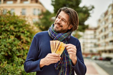 Orta yaşlı yakışıklı bir adam Norveçli kronları parkın dışında tutuyor.