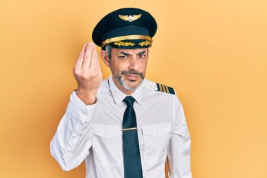 Yakışıklı, orta yaşlı, gri saçlı, uçak pilotu üniforması giyen, el ve parmak hareketleriyle italyan hareketi yapan, kendine güvenen bir adam. 