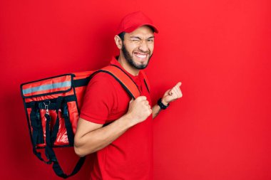 Sırt çantası takmış İspanyol bir adam gururla bağırıyor, zaferi kutluyor ve kollarını kaldırdığı için çok heyecanlı. 