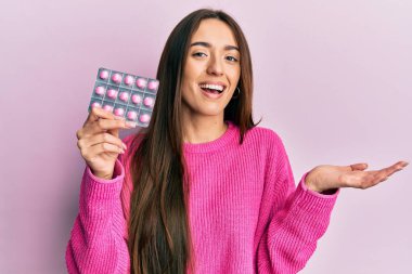 Genç İspanyol kız elinde haplarla başarıyı mutlu bir gülümsemeyle kutluyor ve kazanan el kaldırarak ifade ediyor. 