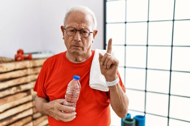 Spor kıyafetleri ve havlu giyen son sınıf öğrencisi üzgün ve üzgün görünüyor, yönünü parmaklarıyla gösteriyor, mutsuz ve depresif.. 