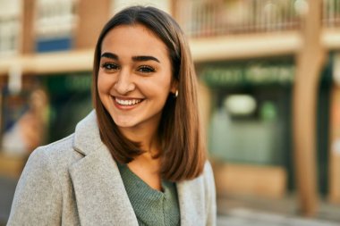 Genç İspanyol kız gülümseyerek şehirde mutlu mesut dikiliyor..