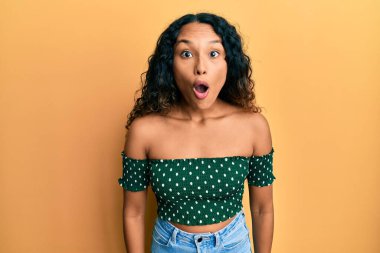 Gündelik kıyafetler giyen genç Latin kadın korkmuş ve ağzı açık şaşkınlık içinde, inançsız yüz. 