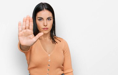 Günlük kıyafetler giyen genç İspanyol kadın avucunun içi gibi şarkı söylemeyi kesiyor. Yüzünde olumsuz ve ciddi bir jest olan uyarı ifadesi. 